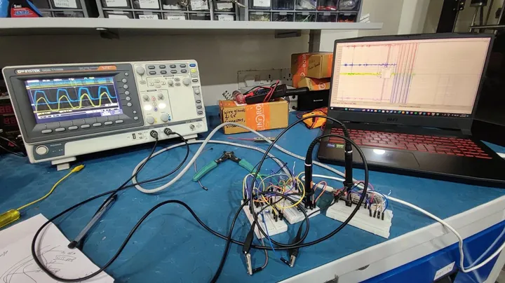 Oscilloscope showing a distorted SPI clock next to breadboarded sensors and a laptop on the lab bench