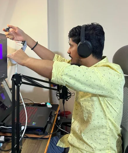 Kumar Utkarsh in a yellow shirt and headphones, testing an Arduino joystick against a ROS 2 node during a live hardware workshop